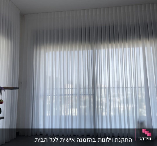 וילון לבן שקוף תלוי על חלון גדול